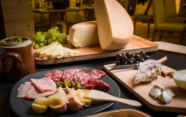 Mesa com queijos, frios e frutas.