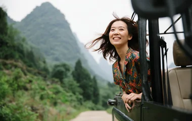 Mulher sorrindo na janela de um veículo.