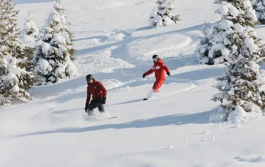 Duas pessoas praticando snowboard.