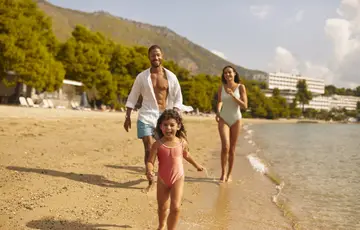 Pai, mãe e filha na praia.