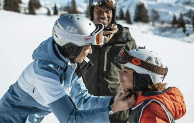 Família ajeitando equipamento para esquiar.