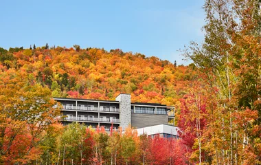 Club Med Quebec Charlevouix rodeado por floresta de árvores com folhas em tons laranjas, vermelhos e amarelos intensos