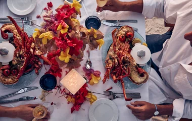 Una pareja, sentada en la mesa de un restaurante, comiendo langosta.
