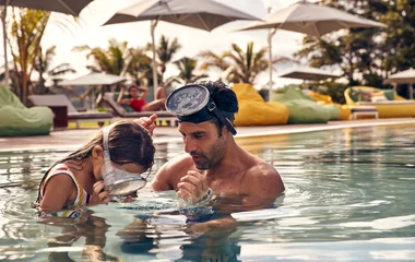 Une petite fille et son père dans la piscine aux Seychelles