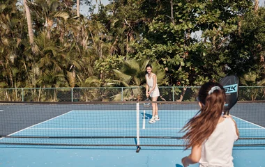 Mãe e filha jogando tênis.