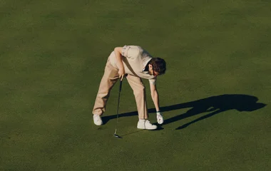 Homem em campo de golf, se preparando para jogar