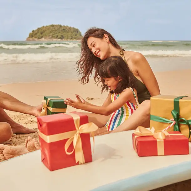family with gifts on beach on Christmas
