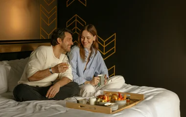 Casal na cama com café da manhã.