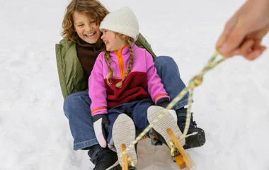 Niños jugando y deslizando en la nieve.