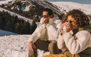 Famille qui prend une boisson chaude à la montagne