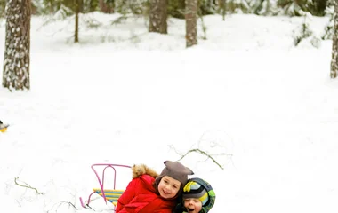 Duas crianças deslizando na neve encima de uma boia inflável