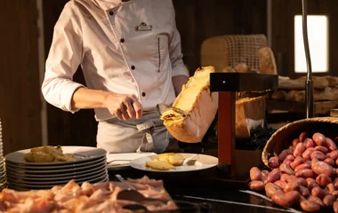 Chef em uma estação de cozinha em um dos restaurantes Club Med servindo queijo em um prato.