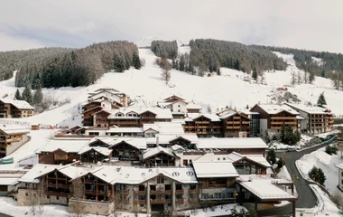 casal em frente a uma varanda com telhado coberto de neve observando a paisagem