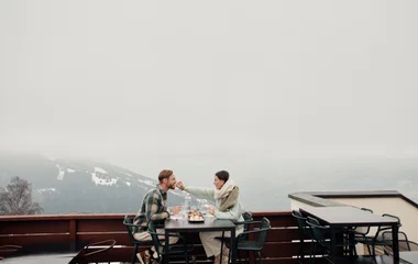 Una pareja comiendo en una mesa de restaurante con vistas a los Alpes.