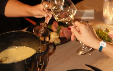 Dos personas brindando en una cena de fondue.