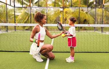 Mãe e filha em quadra de tênis.