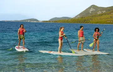 Grupo de amigos praticando stand up paddle.