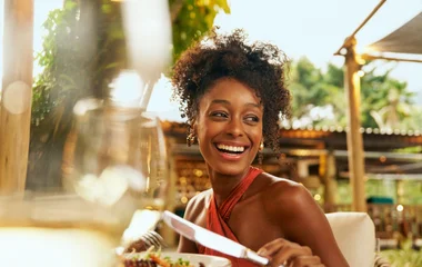Mulher fazendo uma refeição ao ar livre.