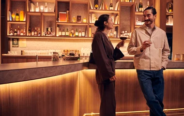 Casal tomando um drink em frente ao bar