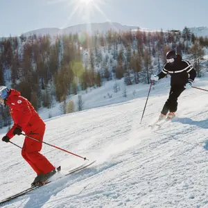 Dois esquiadores descendo montanha de neve