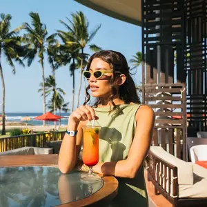 Mujer en Bali tomando un trago con playa de fondo