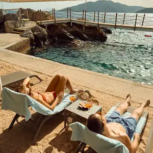 pareja reposeras frente al mar y muelle