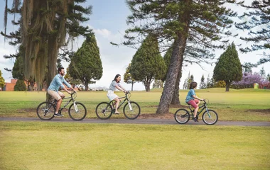 Pai, mãe e filho andando de bicicleta no resort.