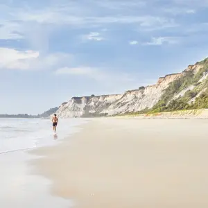 Homem correndo na areia da praia.