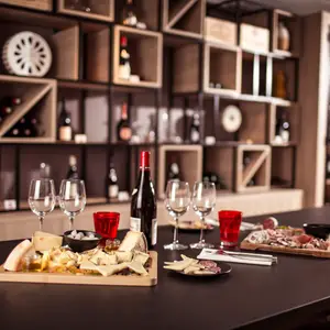 Tábuas de queijo e acompanhamentos ao lado de garrafas de vinho.