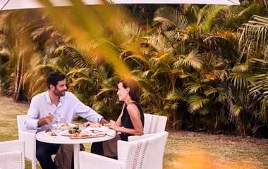 Casal fazendo uma refeição em mesa externa ao restaurante do resort.