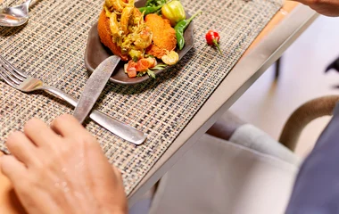 Homem comendo camarão no acarajé em restaurante