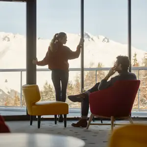 Casal observando a paisagem de neve de dentro do resort.