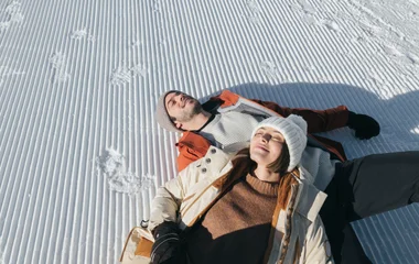 Homem contempla, do alto dos alpes, a paisagem alpina cobert de neve.