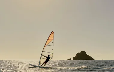 Pessoa praticando windsurf no mar