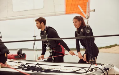 Homem e Mulher em um  barco com roupas de mergulho.
