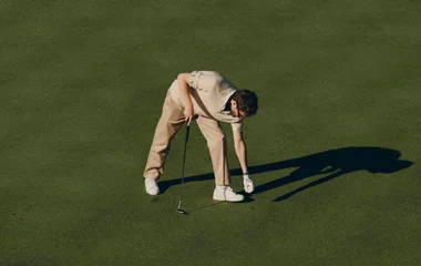 Homem em campo de golf, se preparando para jogar