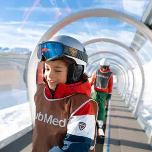 Criança andando com a roupa de esquiar do Club Med.