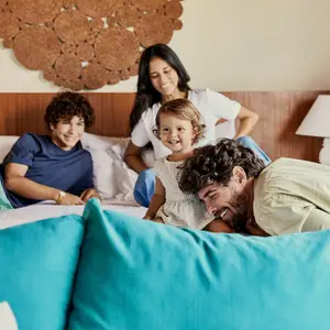 Pai, mãe e dois filhos na cama da suíte do resort.