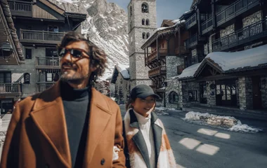 Adultos passeando nas ruas com montanhas nevadas ao fundo