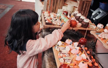 Criança apontando para os doces na vitrine.