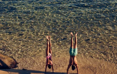 Hombre y mujer haciendo parada de manos cerca del mar.