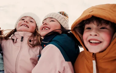 Foco em três crianças de gorro na neve