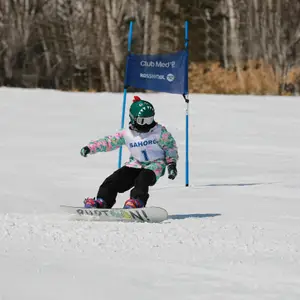 Criança praticando snowboard em resort do Club Med.