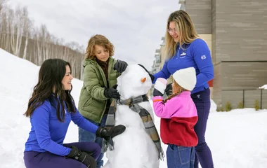 Duas crianças brincam de fazer boneco de neve junto a um GO