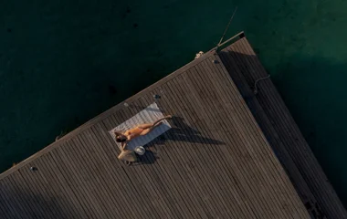 Mulher deitada em deck de madeira próximo ao mar.