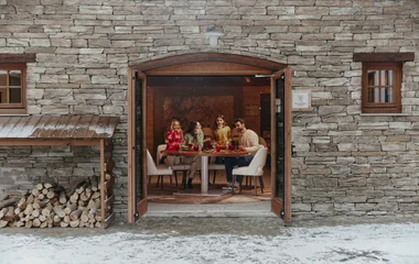 Família jantando de portas abertas, em seu chalé nos Alpes da Itália