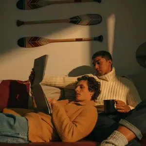 Casal sentado em um sofá, lendo um jornal e tomando café.