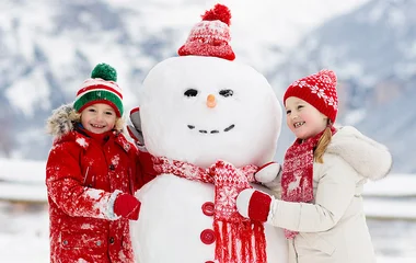 Crianças ao lado de boneco de neve.