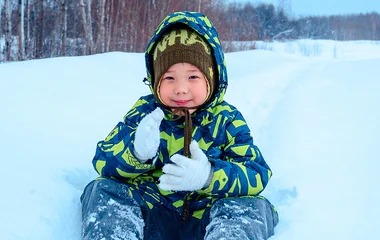 Criança com touca e luva na neve.