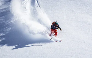 Homem descendo e fazendo poeira de neve.